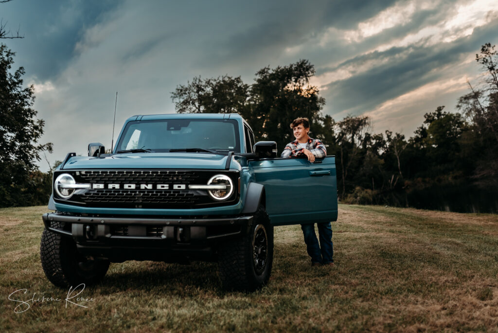 Senior photo of a senior guy with his ford bronco and a beautiful sunset sky in the quad cities
