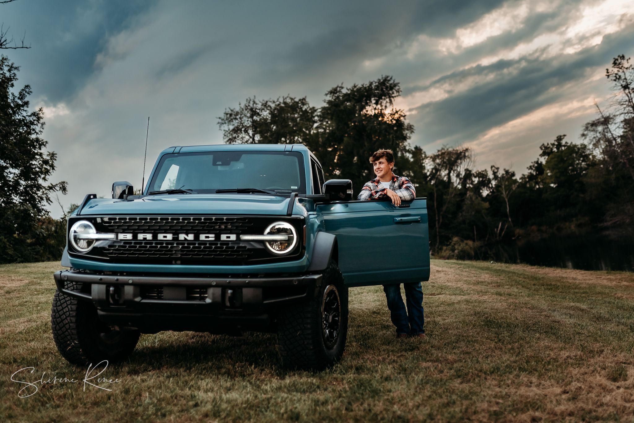 Senior photo of a senior guy with his ford bronco and a beautiful sunset sky in the quad cities